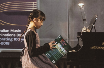 A girl holding music book at the piano 
