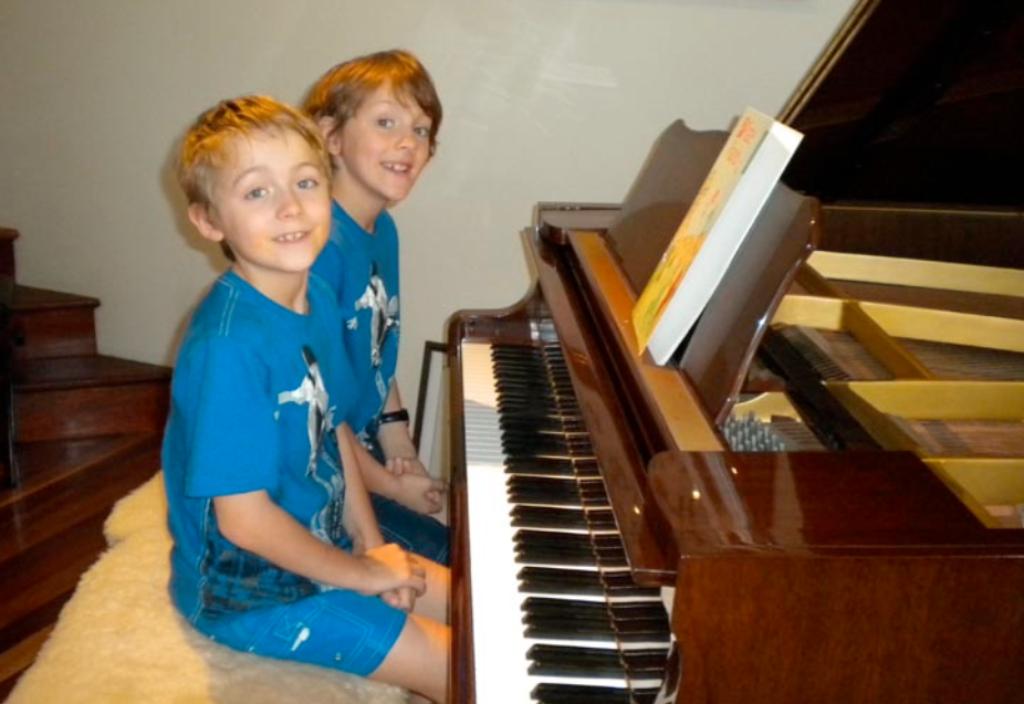 two boys sitting at the piano